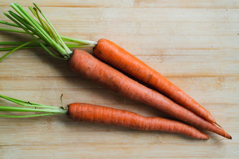 Three carrots on a wooden surface