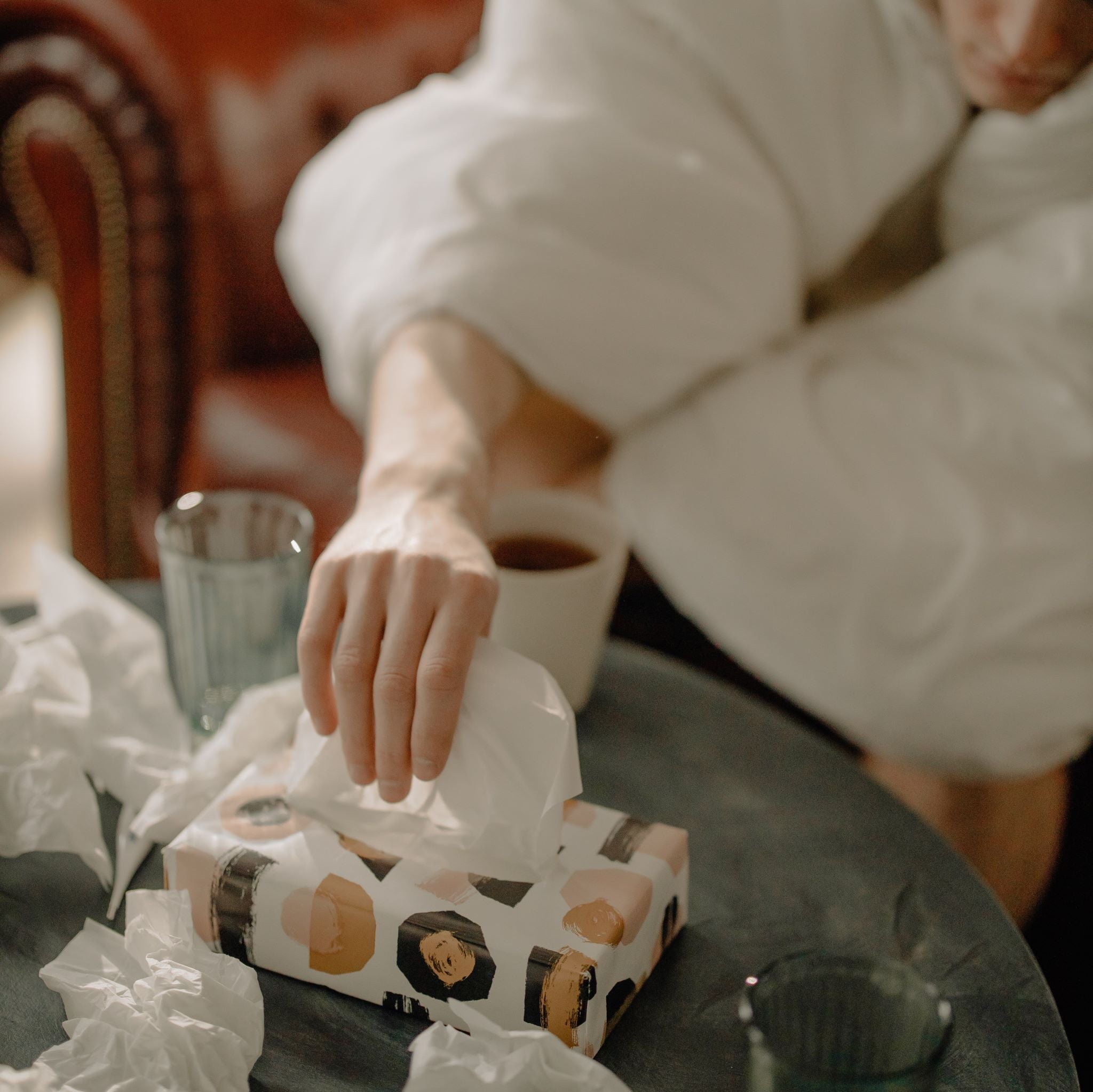 Person reaching for tissues due to a cold.