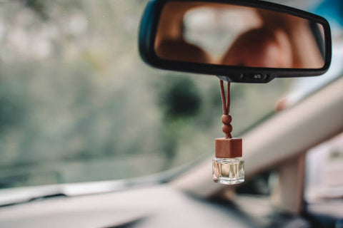 Small freshener vial hanging from a rear view mirror
