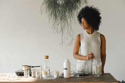 Woman at her candle making bench with various candle making equipment on the bench