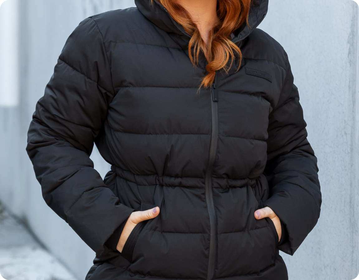 close-up image of a woman wearing a Muscle Nation puffer jacket.