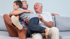 Father's Day Facts Blog Image. 3 Generations. Father, Son and Grandson embracing on a sofa.