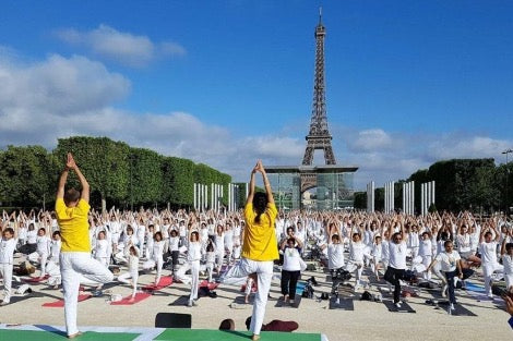 Des personnes célébrant la journée internationale du Yoga sous la tour Eiffeil