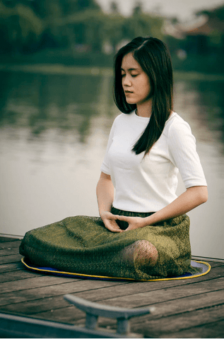 Une femme pratiquant la respiration ujjayi au bord d'un lac