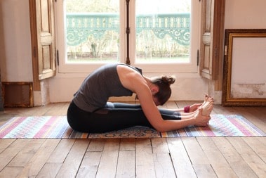 une femme faisant du yoga - une pose de pli vers l'avant assis