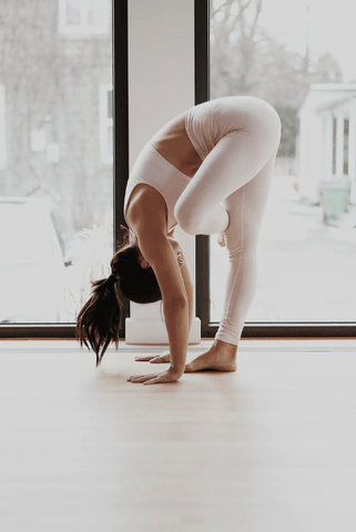 Une femme réalisant une variant de la posture de la cigogne à l'intérieur