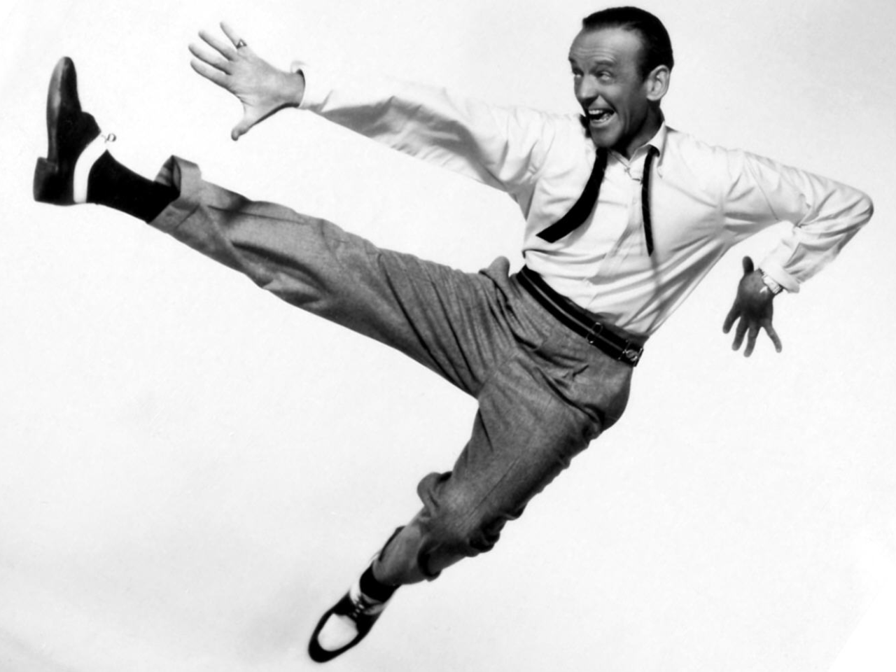 Fred Astaire dancing with a big smile on his face. Picture in black and white.