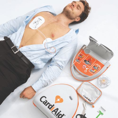 Unconscious man lying down after a heart attack, with CardiAid automated external defibrillator (AED) attached on him for life-saving purposes