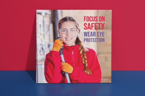 An eye safety poster of a young woman wearing safety glasses and orange gloves smiling as she works in a warehouse with a safety slogan in the top right corner.