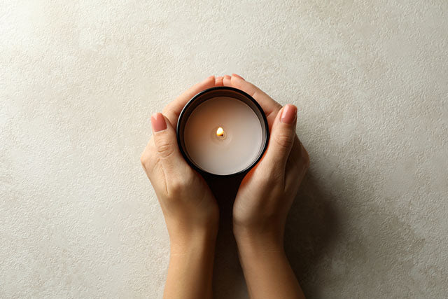 hands holding scented candle top