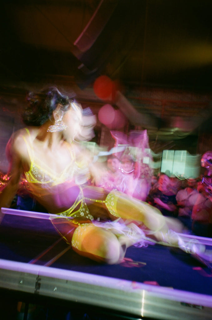 motion-blur bushwig performer on sitting on stage in lingerie.