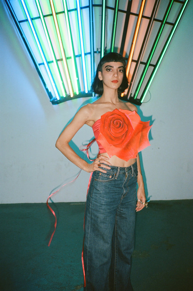 @meliikabi posing in floral top in front of lights.