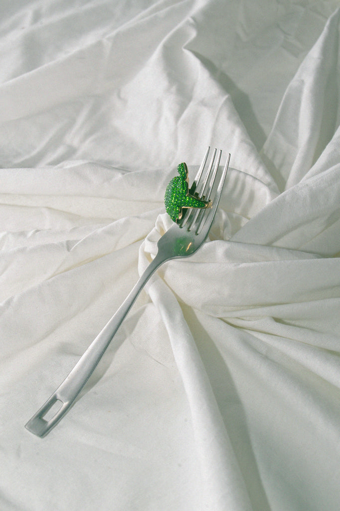 still life of crystal green turtle ring on fork.