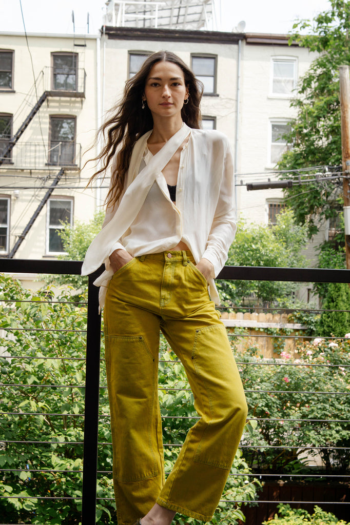 bruna posing in jeans and shirt on balcony.