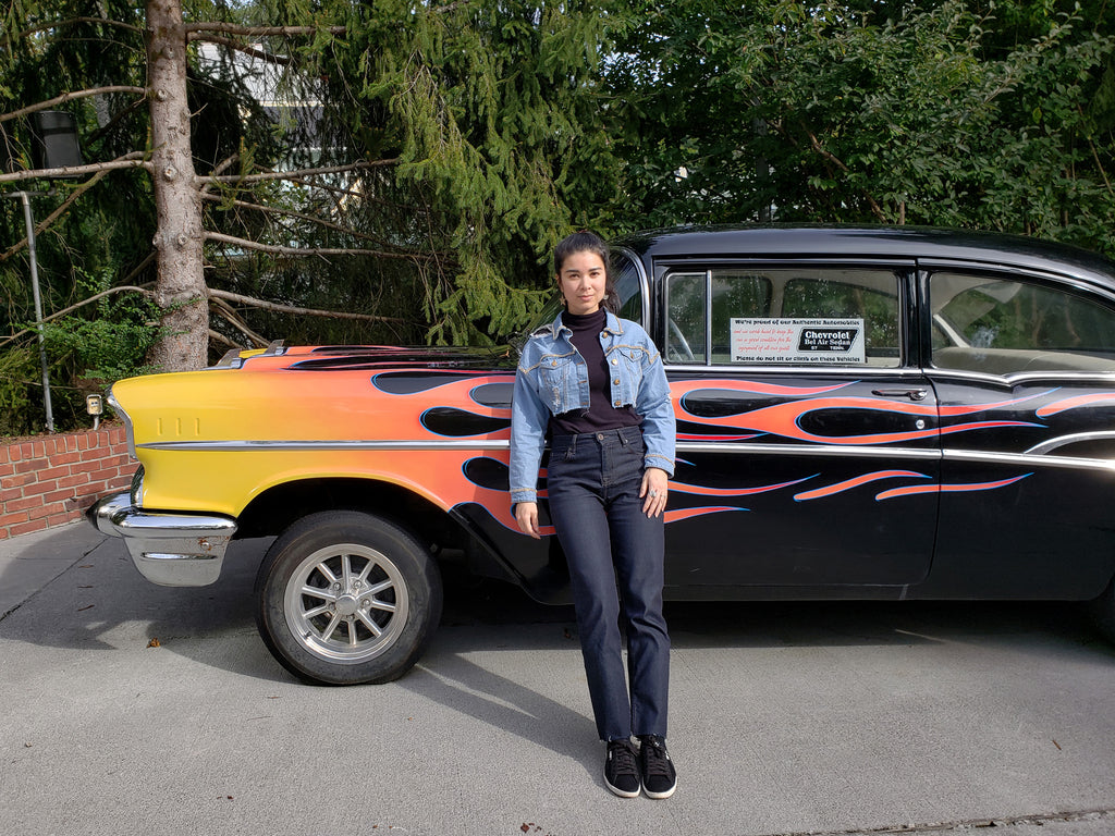 person leaning at black old car with flames detail.