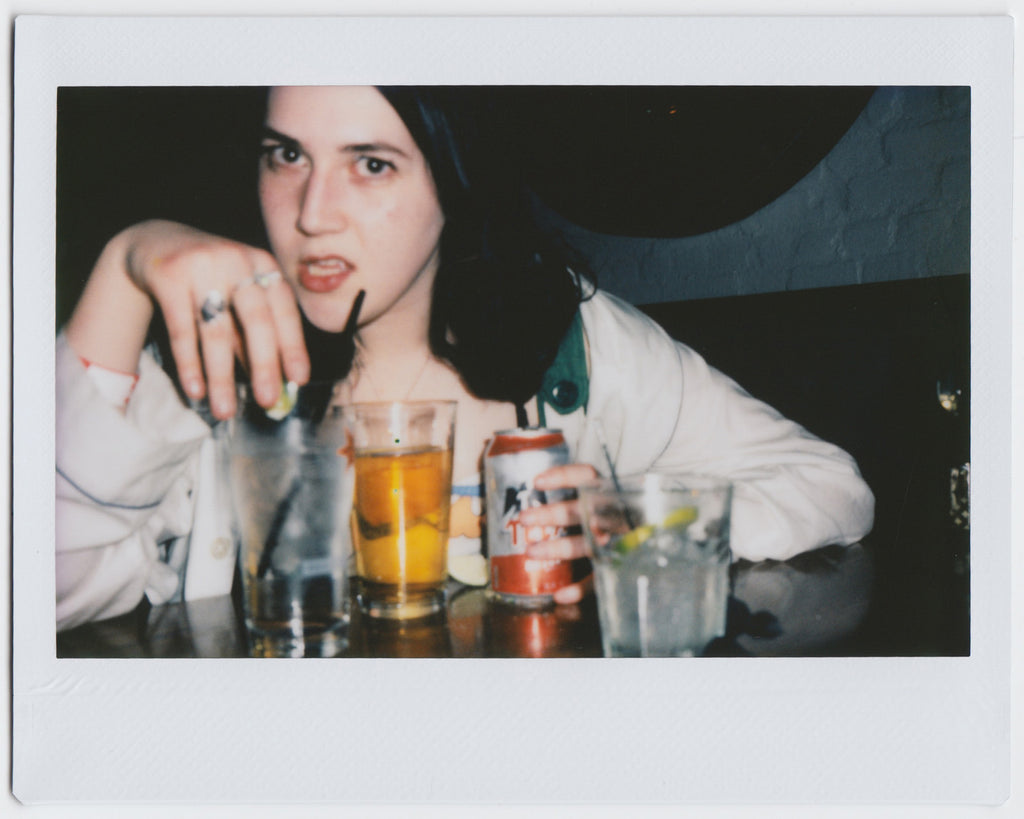 person posing with four drinks, close-up shot - polaroid style. 