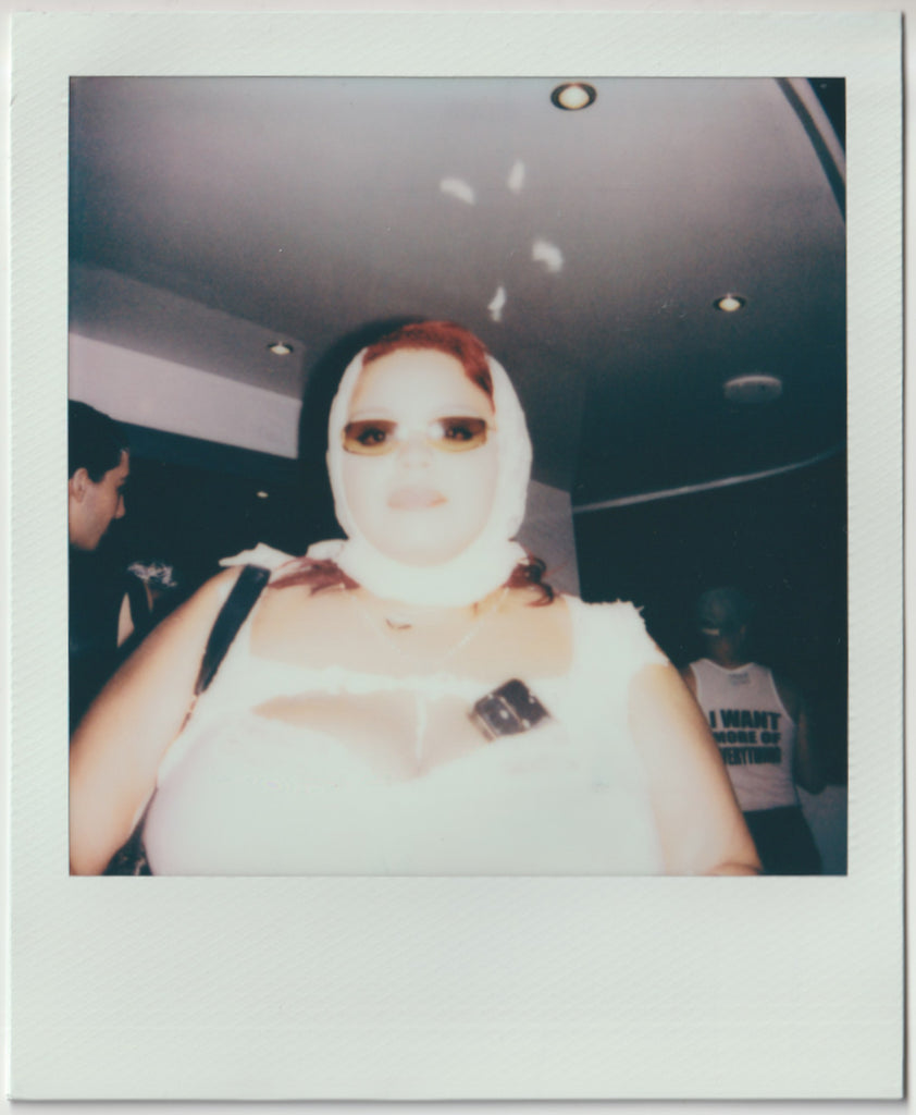 employee posing to the camera, in a look all white - polaroid style.
