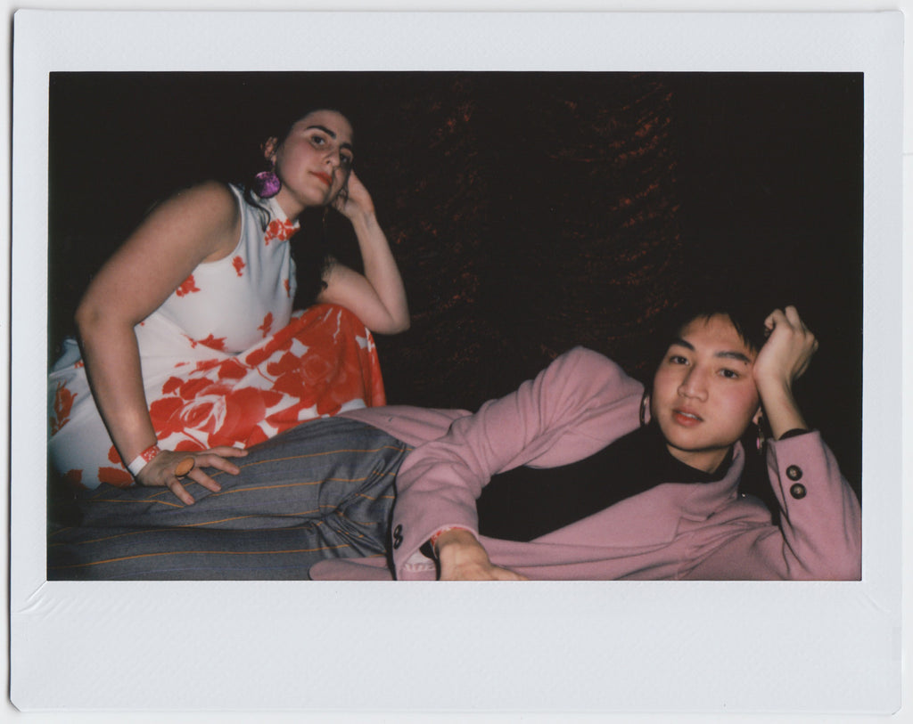 duo posing: one lying on the floor with head resting on hand, the other crouching in the background - polaroid style