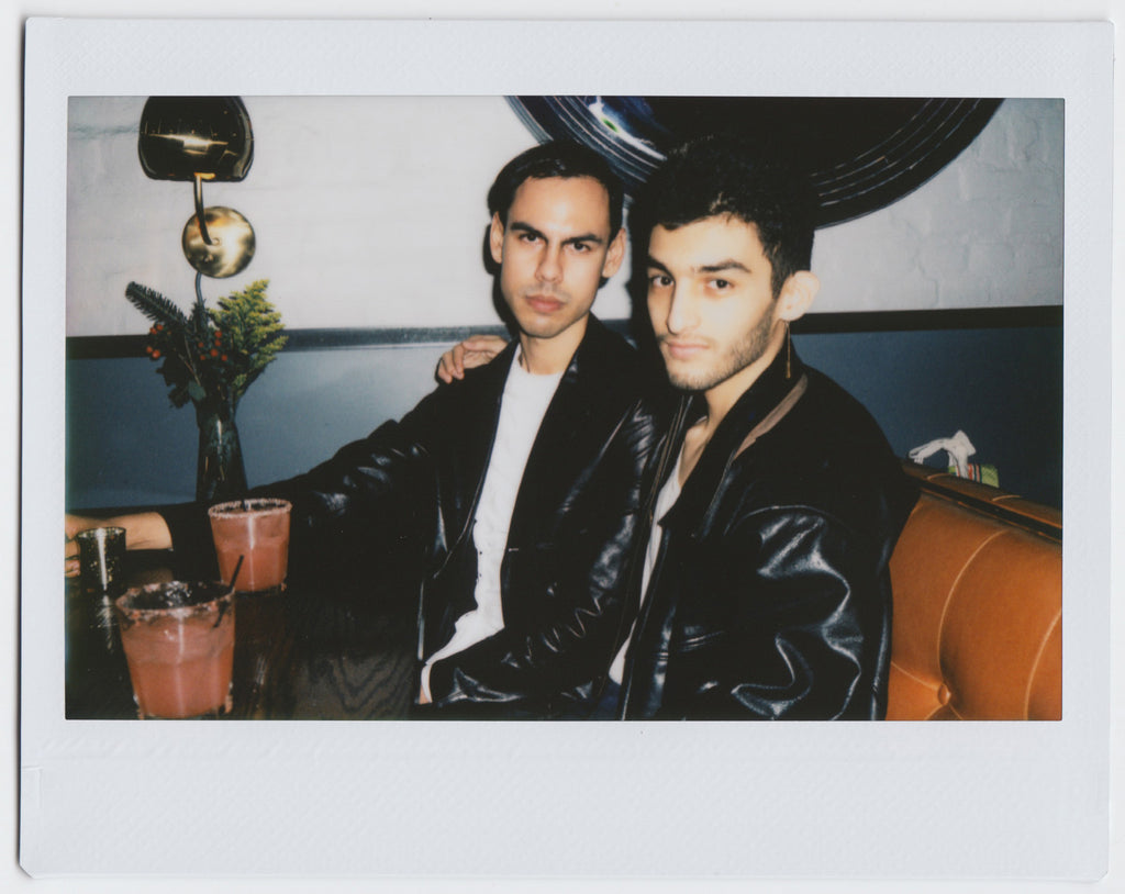 two people sitting together, drinks on table - polaroid style. 