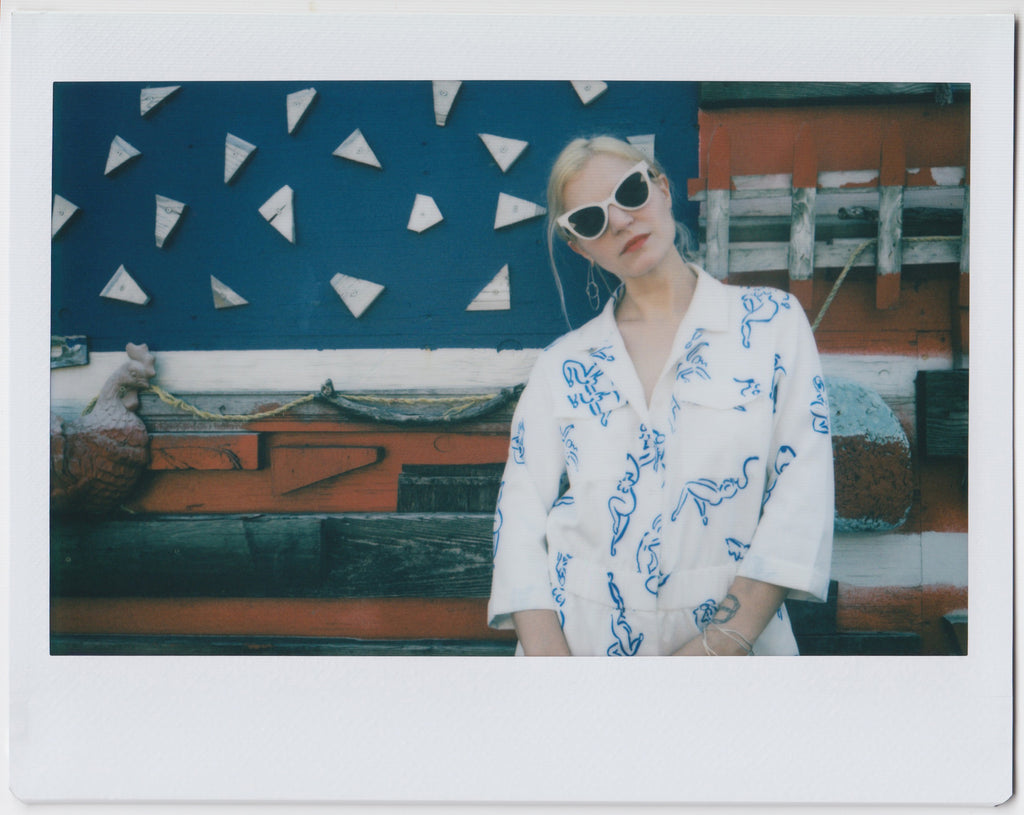 model in jumpsuit with abstract human form drawings in front of a wooden abstract american flag.