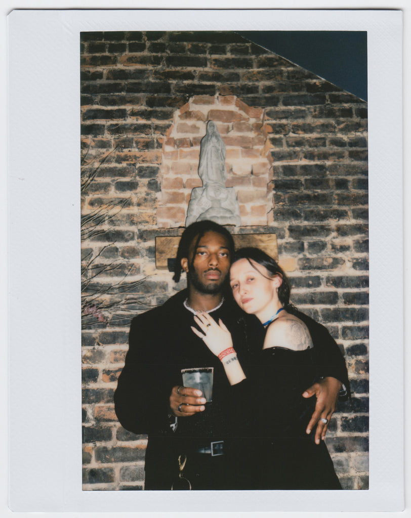 duo posing close to each other, saint image in background - polaroid style. 