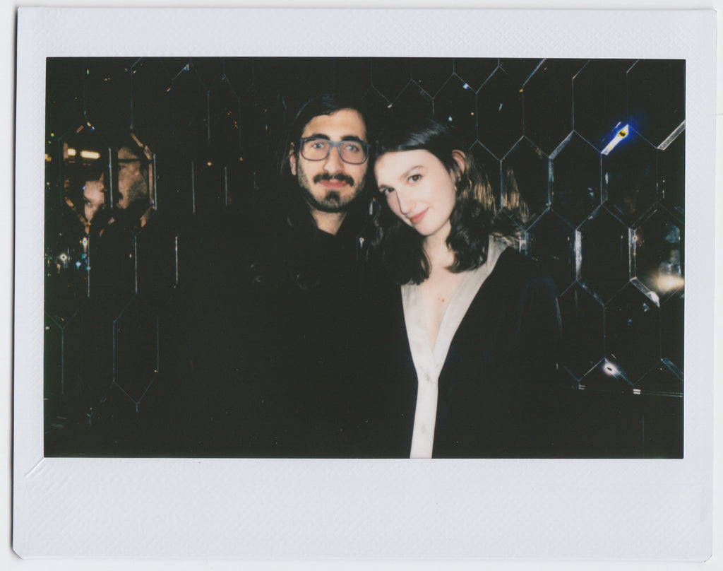 duo posing to the camera, mirrored wall in the background - polaroid style.