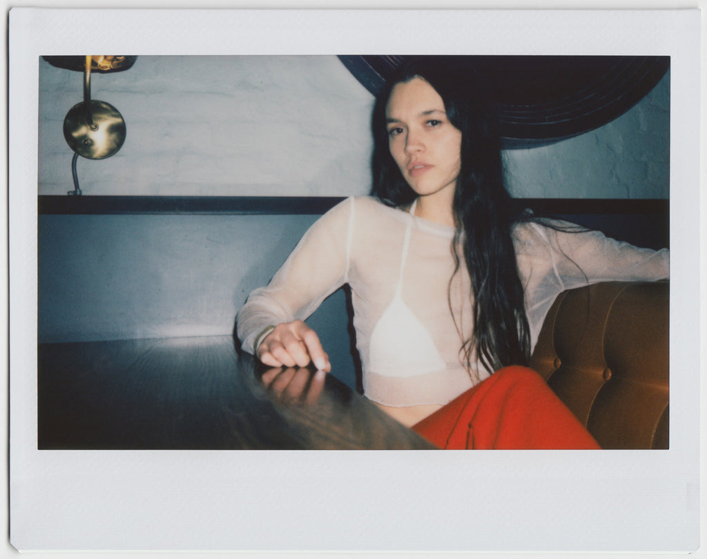 person posing at a table, hand resting, looking directly at the camera - polaroid style. 
