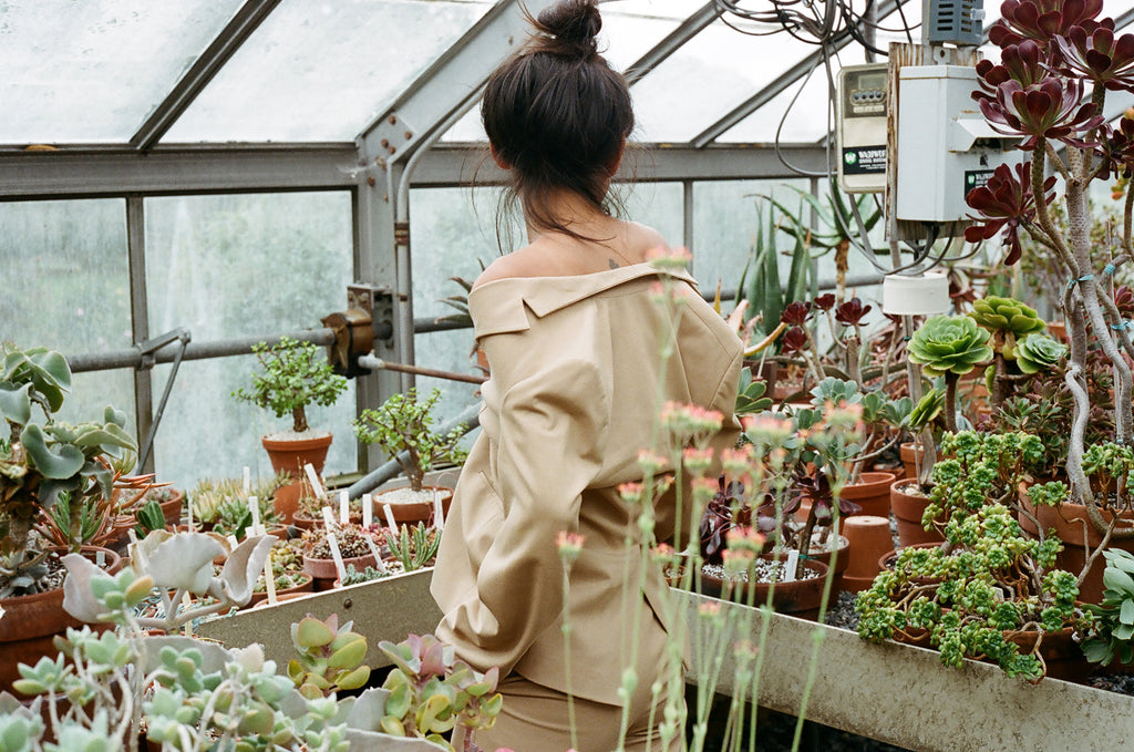 portrait of back of model with suit off shoulders surrounded by succulents.