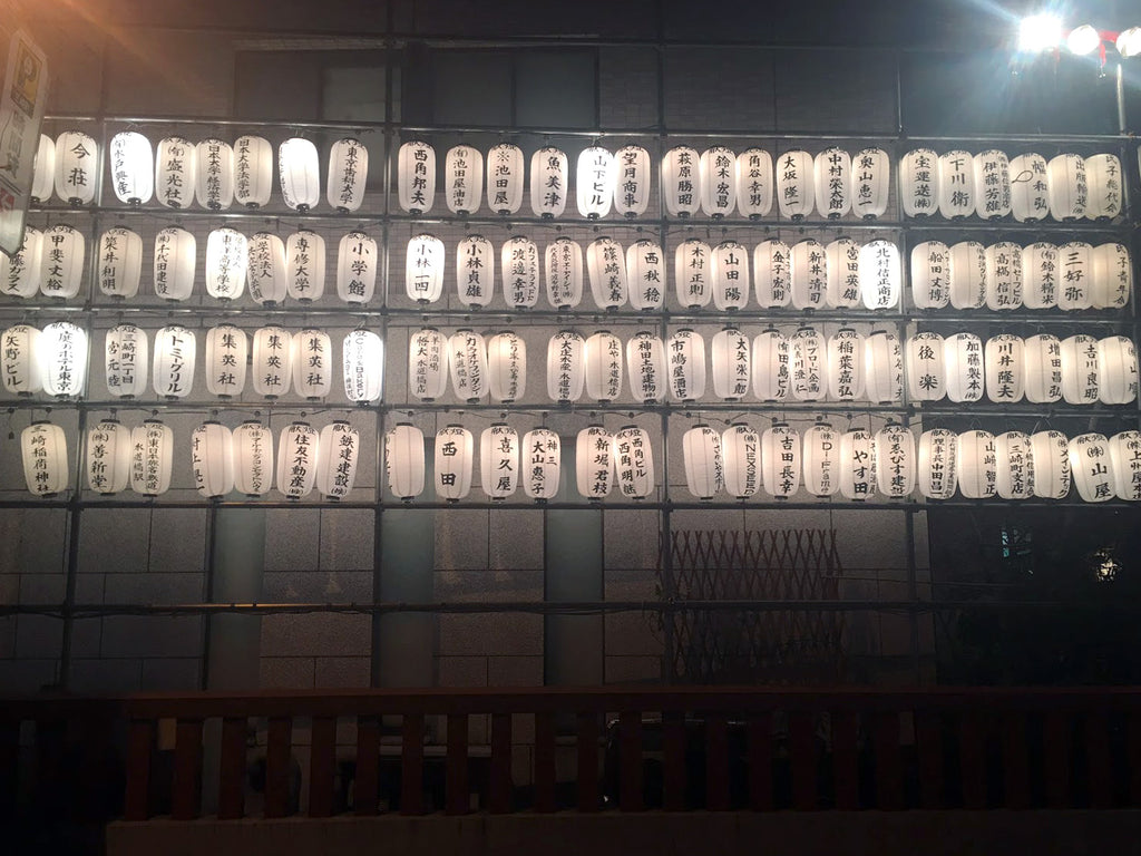 a large wall of paper lanterns lit up at night.