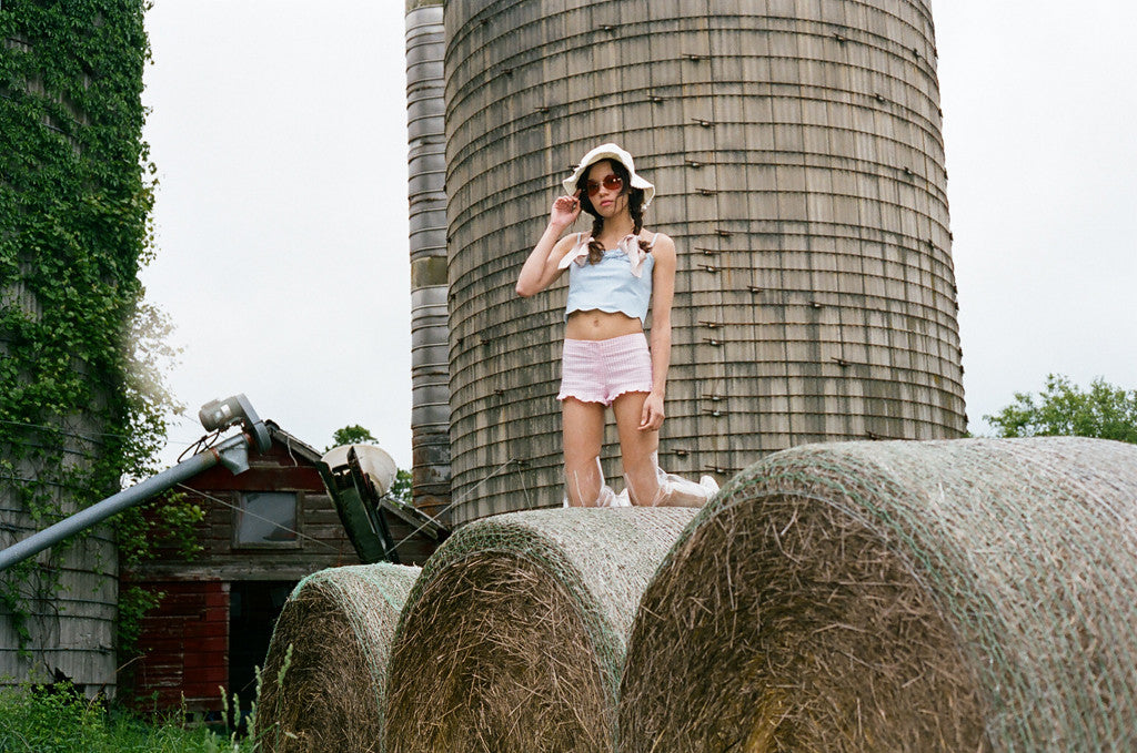 model on top of bales of hay with silo behind.