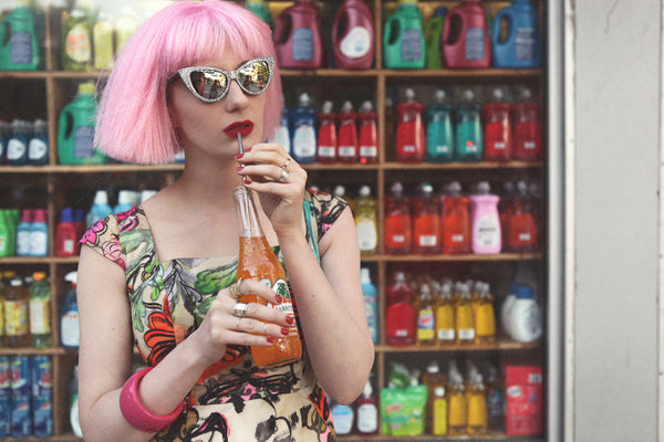 portrait of drinking orange soda in front of bodega.