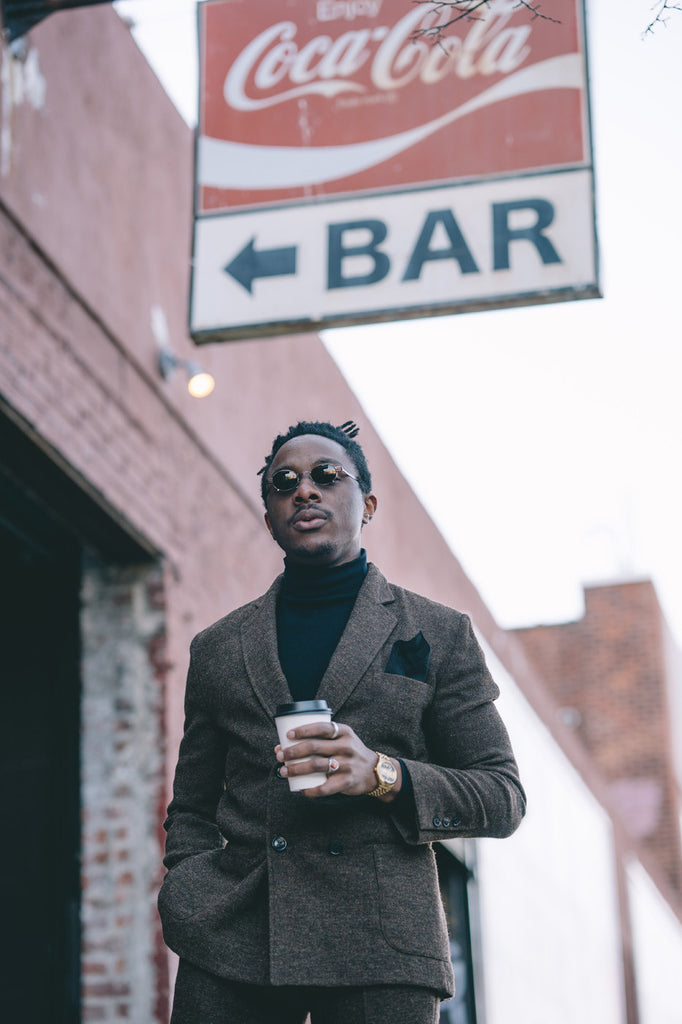 osi holding coffee cup underneath 'enjoy coca-cola', 'bar' sign.