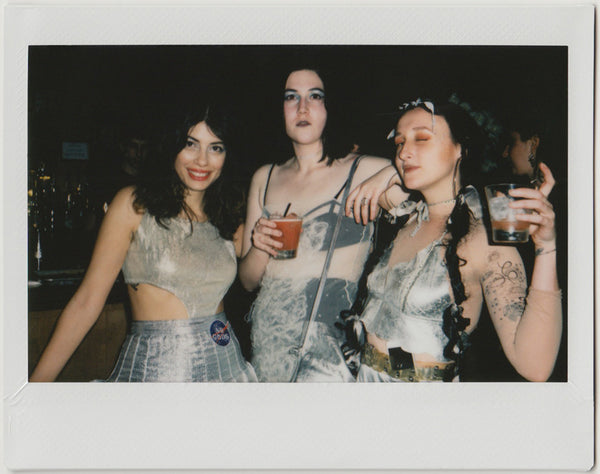 three employees posing for the camera, holding drinks - polaroid style.