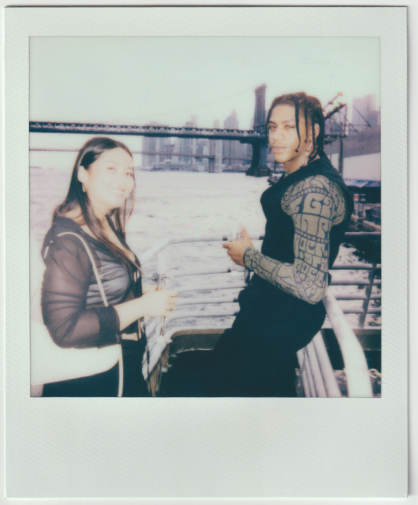 two people looking to the camera, river/bridge in the back.