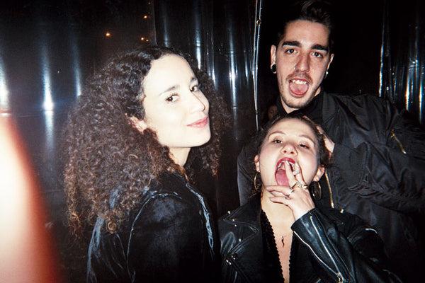 three people posing for the camera – one with a slight smile, the other two sticking out their tongues.
