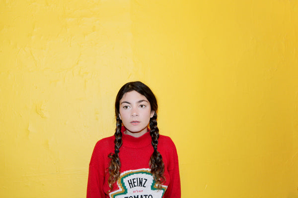 aisha gunnell in heinz ketchup sweater in front of yellow wall 