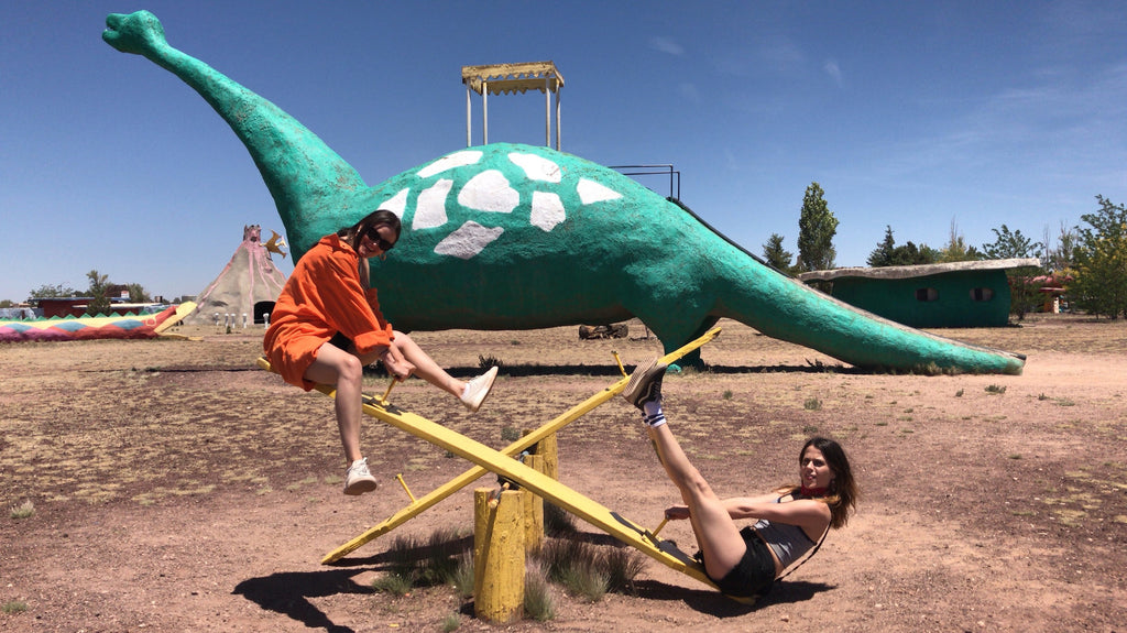 two people playing with a dinosaur slide in a park.