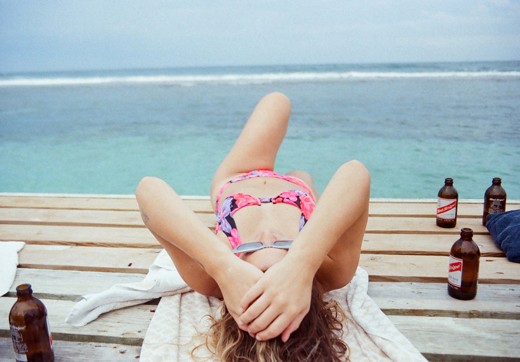 a person in a floral bikini laying on a wooden deck.