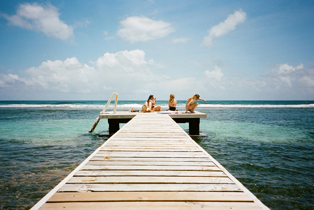 group of people people sitting on a wooden dock in the ocean.