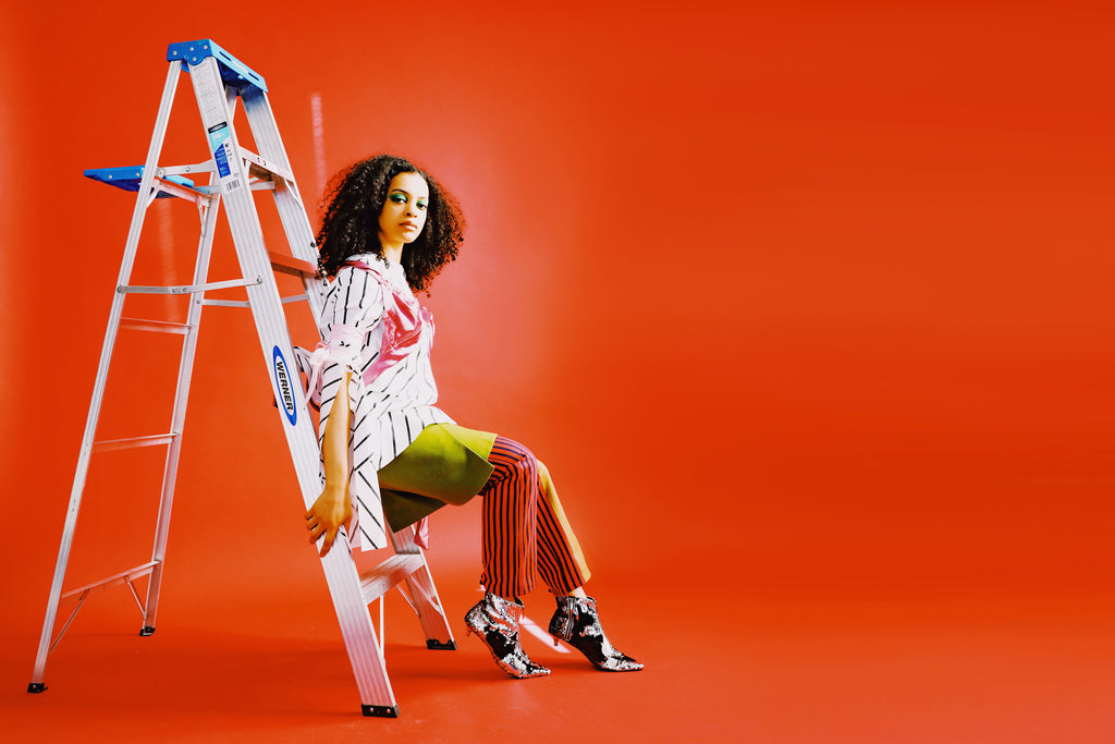 model seated on step ladder.