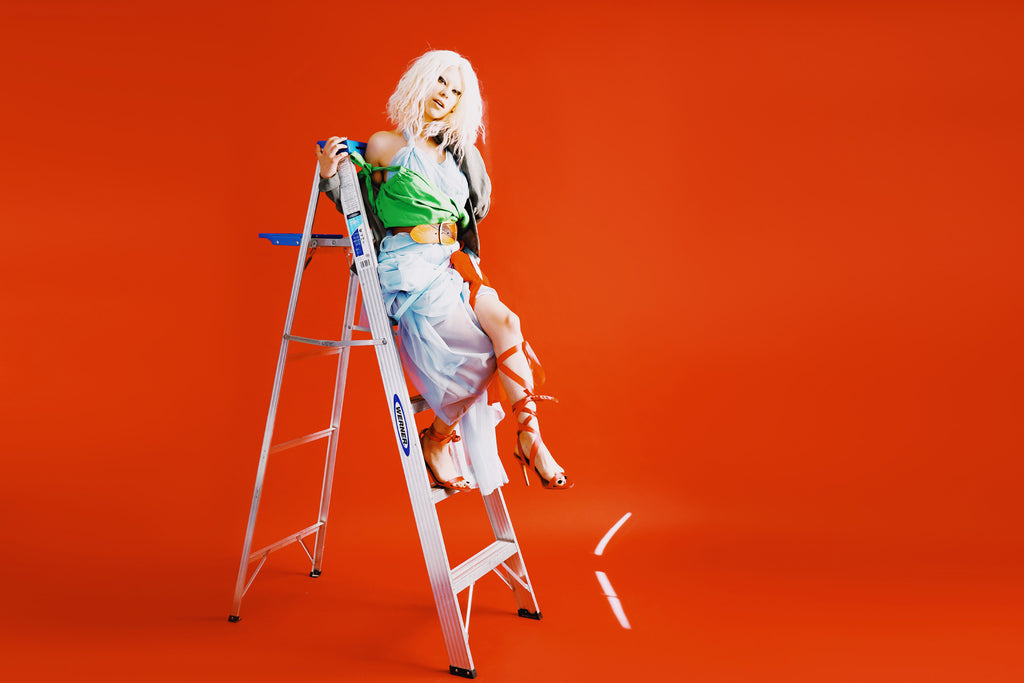 model in conceptual look sitting on a step ladder.