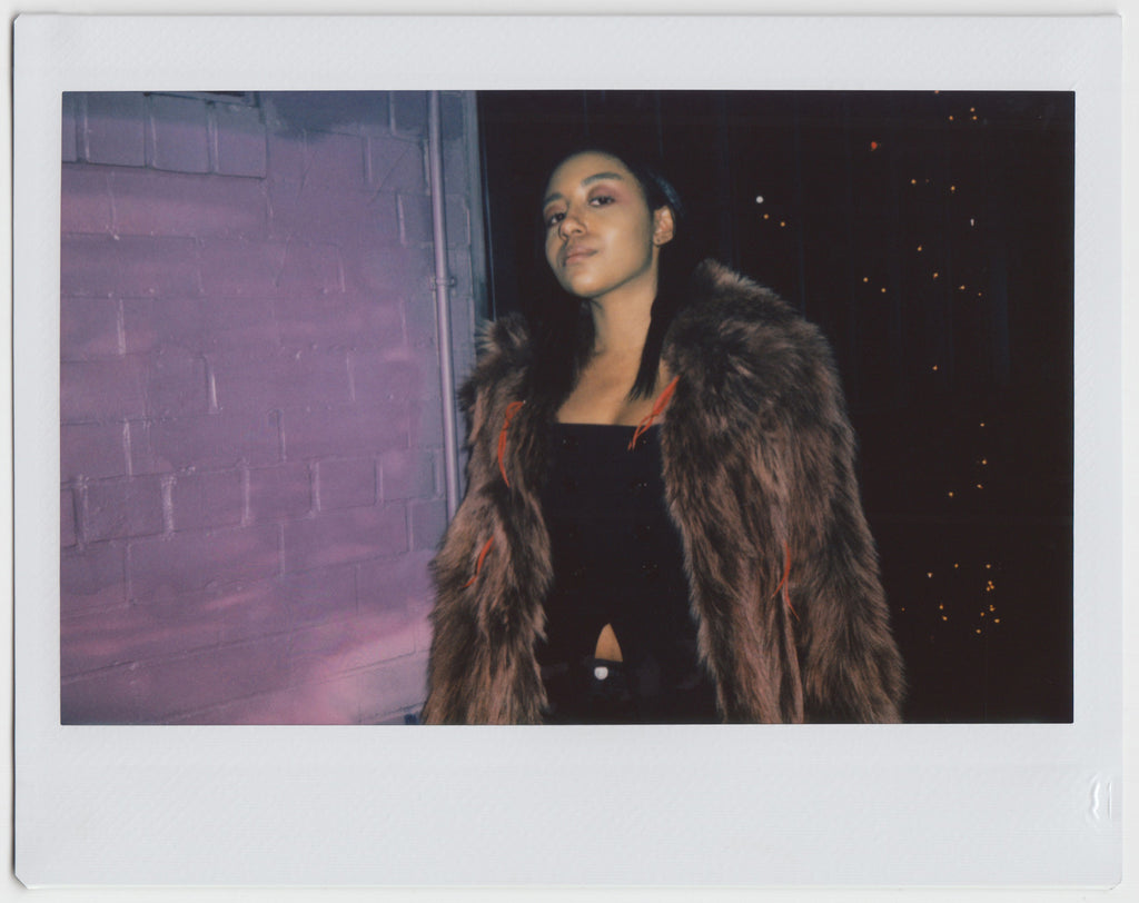 person posing with chin up, wearing a fur coat - polaroid style. 