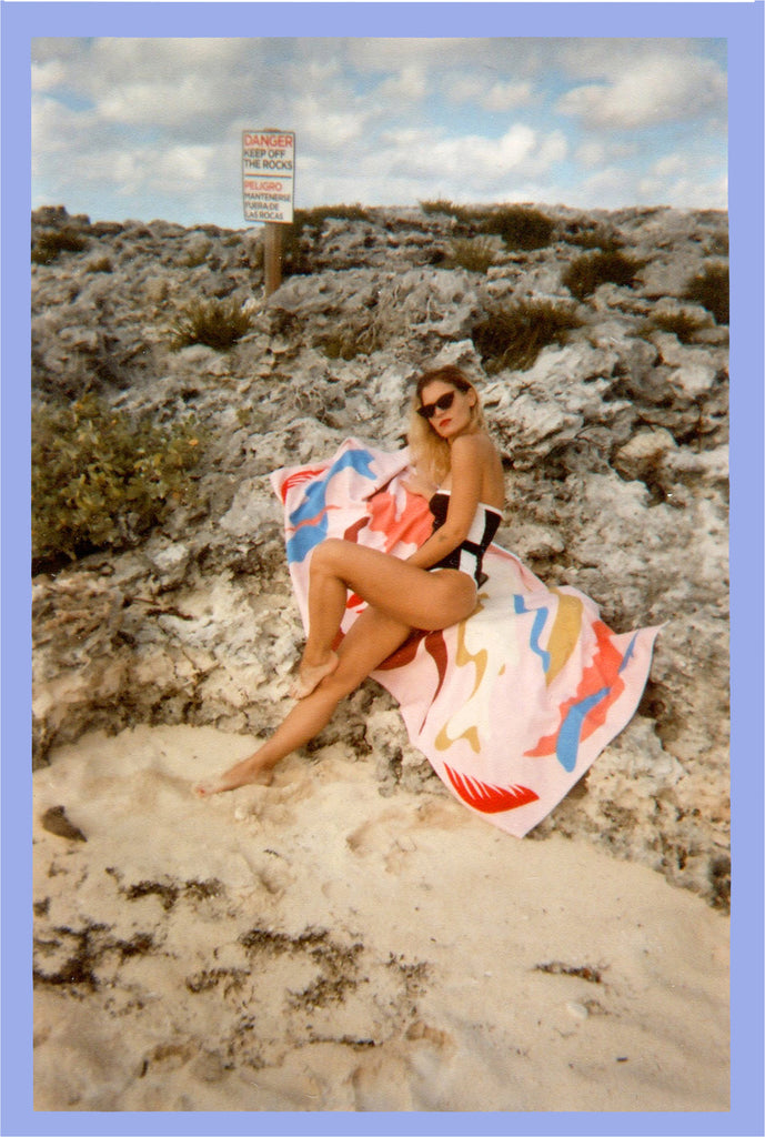 person with bikini posing at rocks by the beach