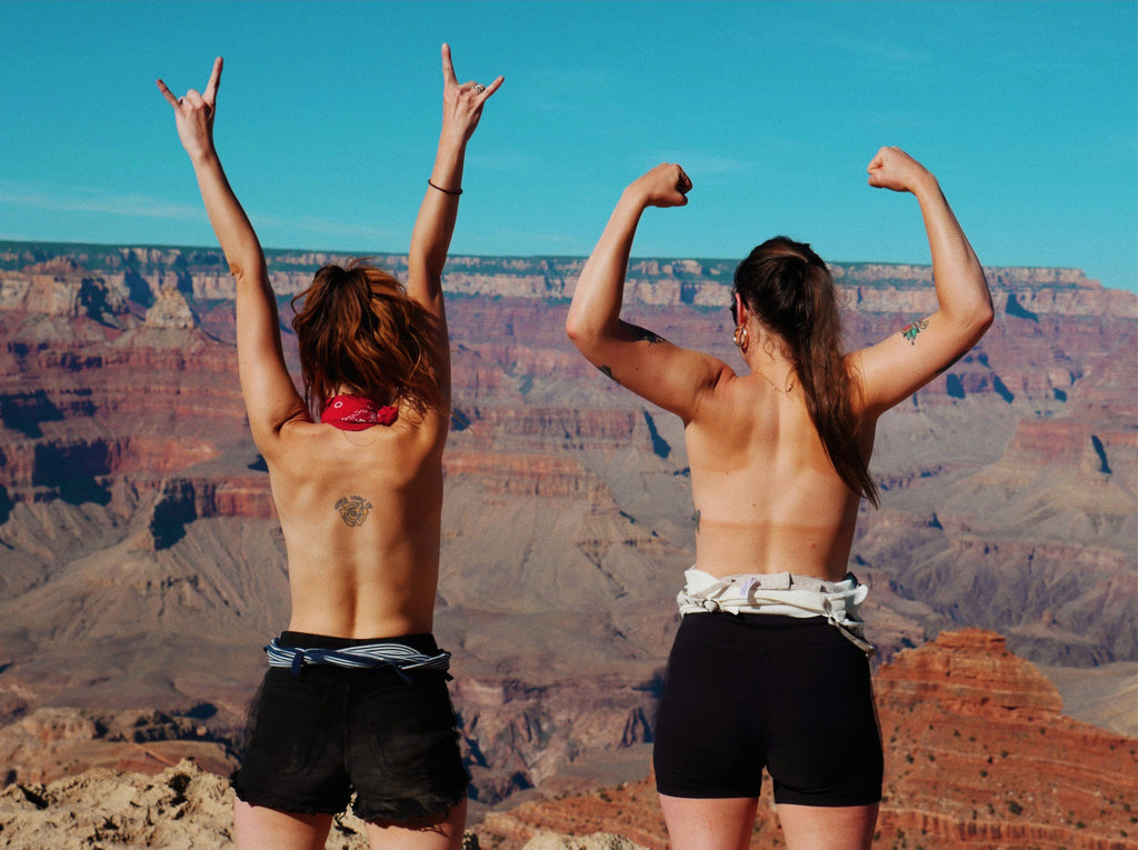 two people with their arms raised in the air at the grand canyon.