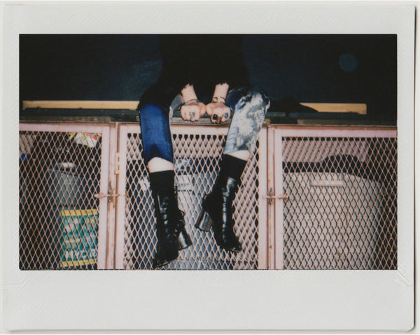 hailey sitting on trash cage featuring rings, pants and boots.