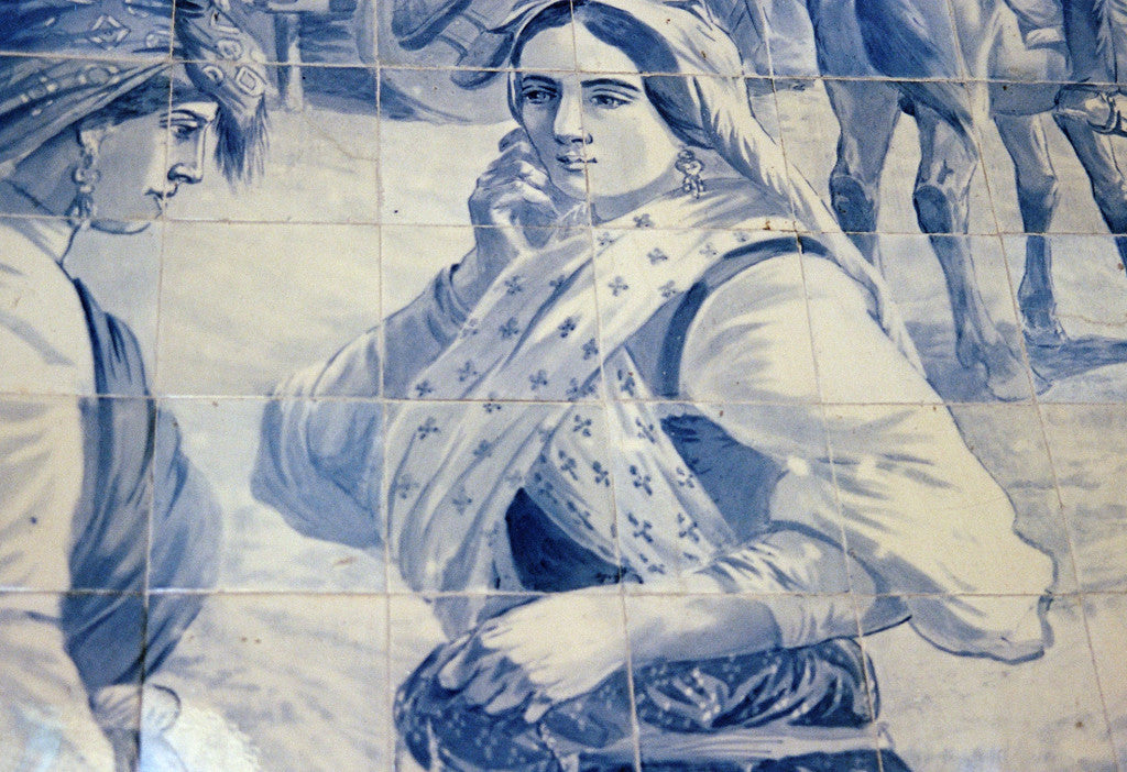 a blue and white tile depicts a person resting face in their hands.