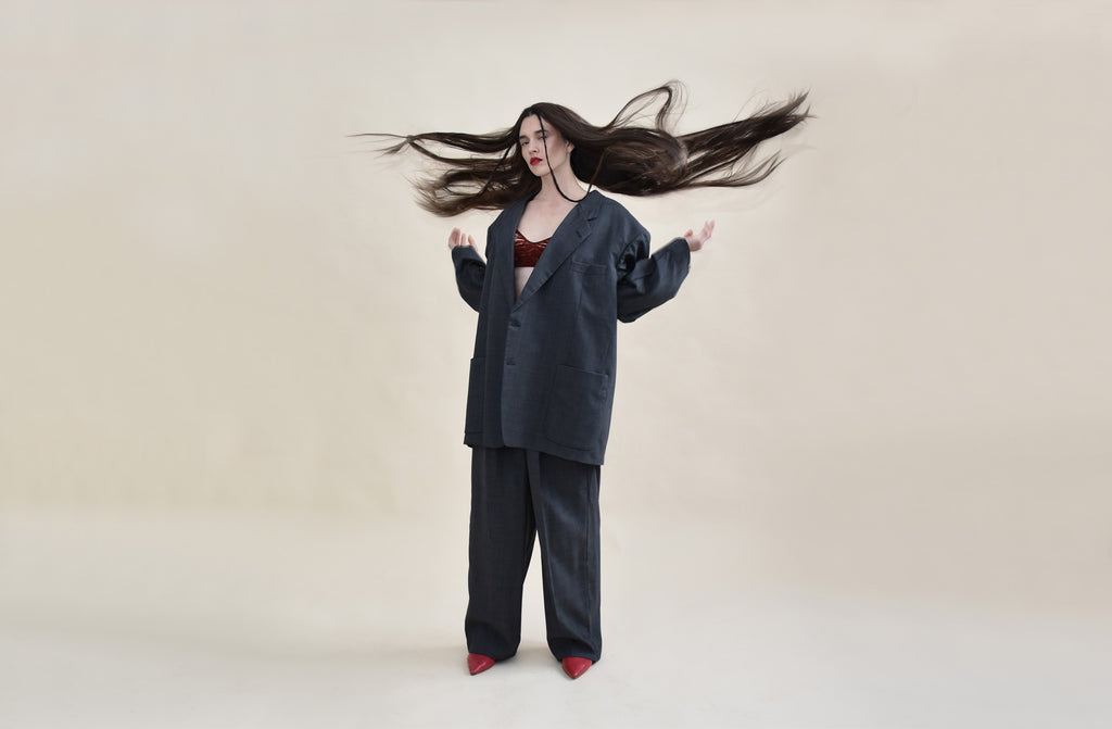 model in oversized suit flicking long hair in the air.