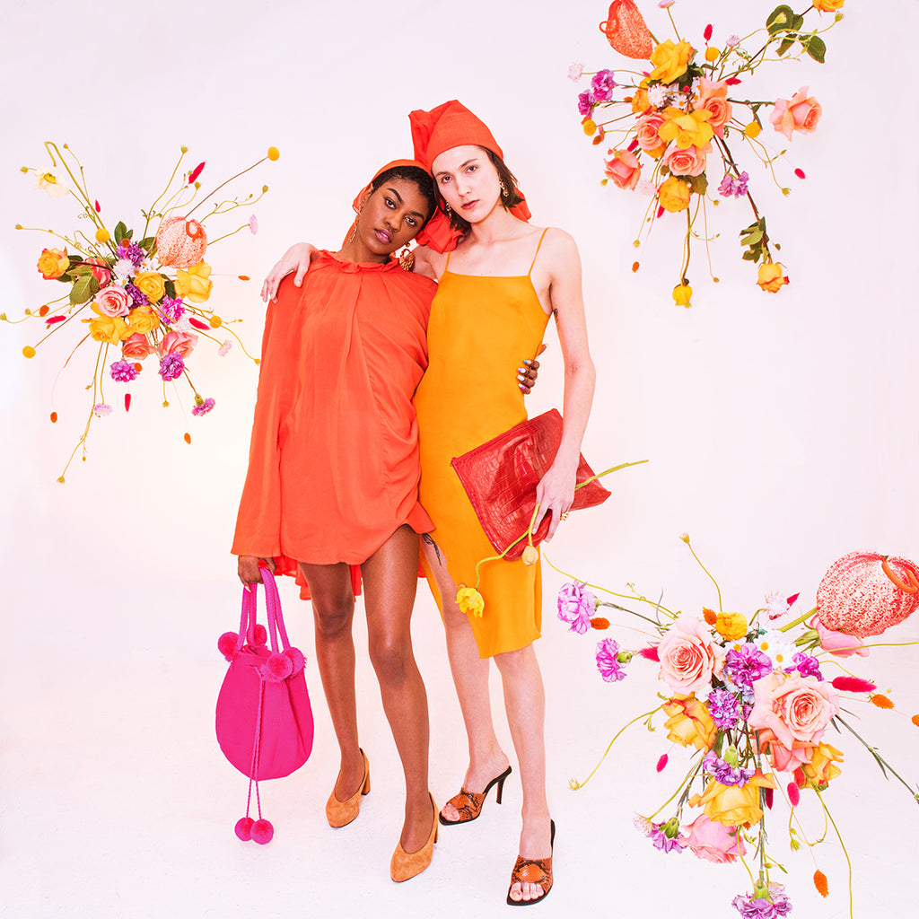 two models posing together amongst floral arrangements. 