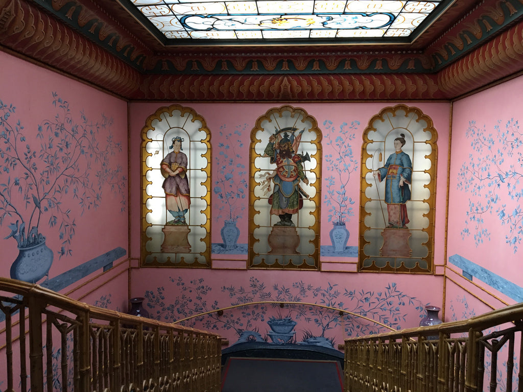 the stairway leading to a pink room with paintings on the walls.
