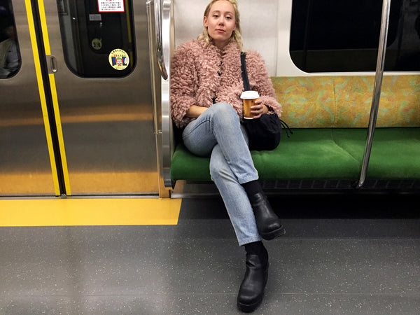 person holding coffee, sitting on the subway.